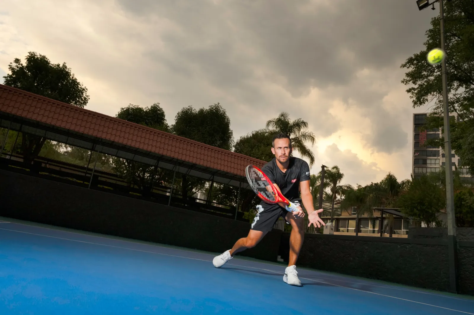 Miguel stretches for a low volley under a stormy sky.