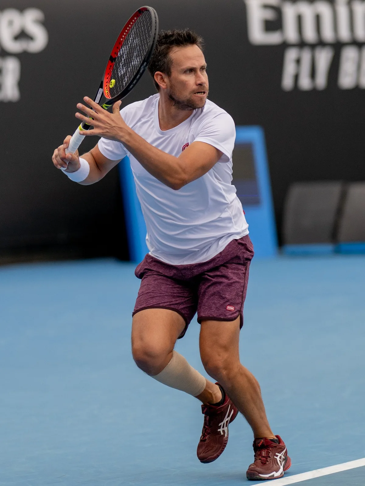Miguel hits a forehand on a hard court during a tournament.