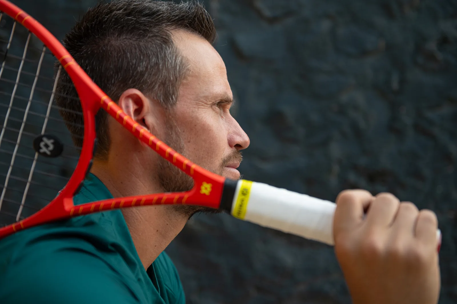 Close-up profile of Miguel with the racket resting on his shoulder.